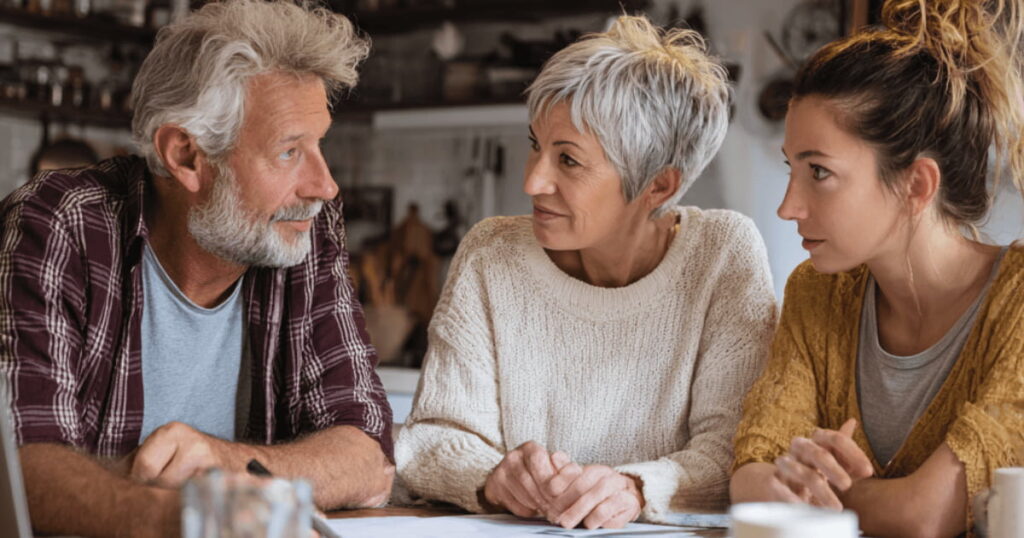 "Senior couple having a serious conversation with adult daughter about downsizing decisions"
